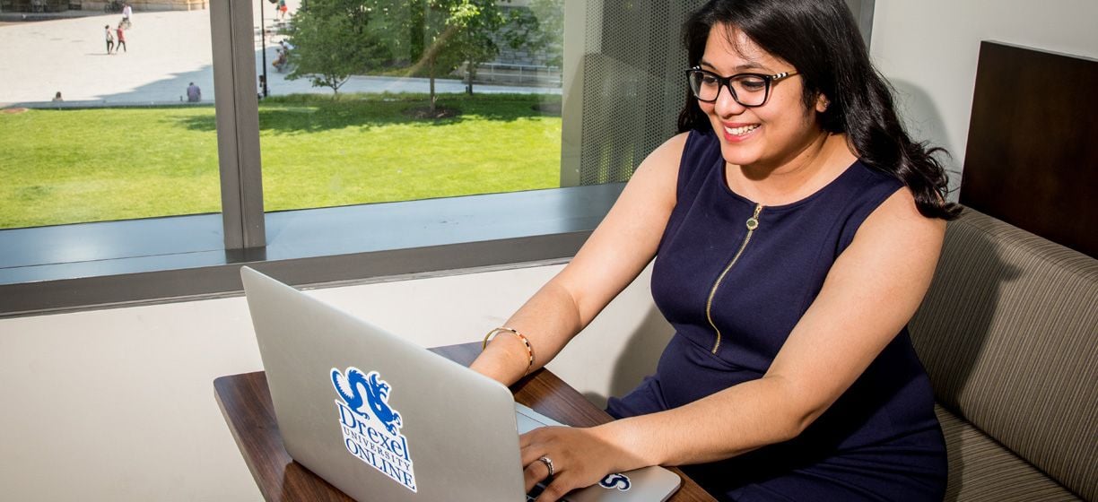 Drexel online student stilling at a laptop computer in her apartment